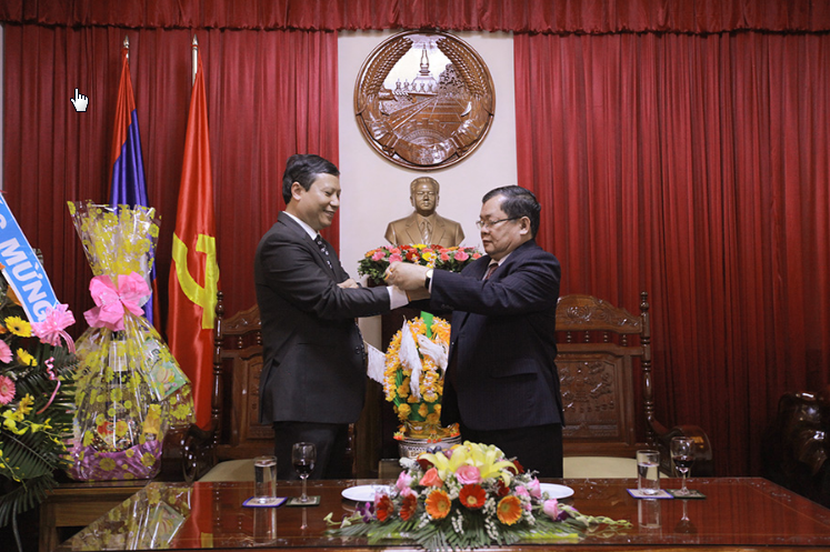 Ông Khamsene Phommaseng - Tổng lãnh sự Lào buộc sợi chỉ tay may mắn và gửi lời chúc tốt đẹp đến PGS.TS. Lê Quang Sơn -  Phó Hiệu trưởng Nhà trường.